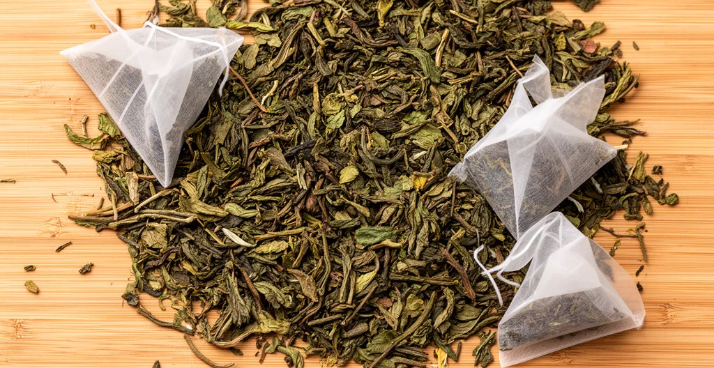 Feuilles de thé bio séchées avec sachets pyramides recyclables sur fond bois